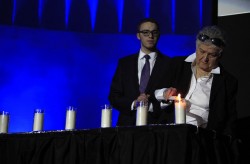 Holocaust survivor and speaker Mrs. Sally Frishberg lights a candle at the ceremony, as SHEM Vice President David Freilich looks on.